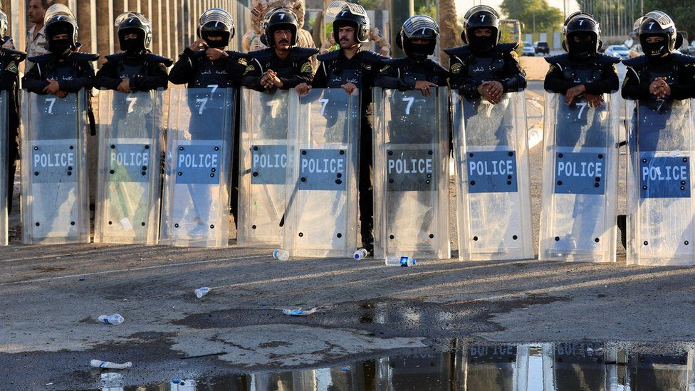 A row of police officers holding riot shields