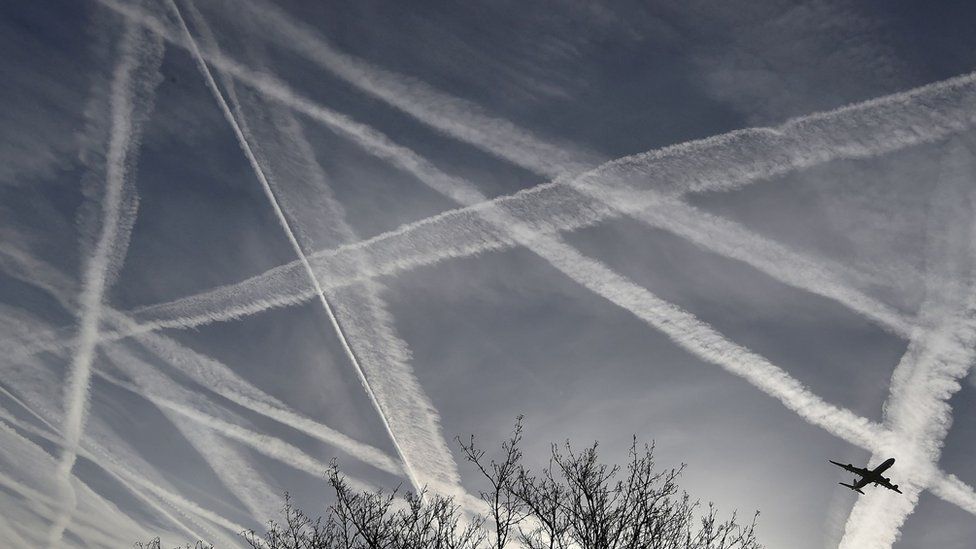 Contrails crossing over in the sky and airplane visible